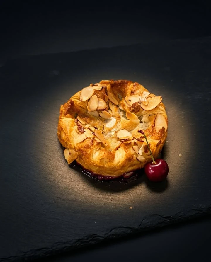 A cherry almond danish with golden pastry layers and a bright cherry center