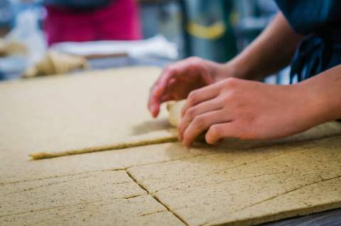 A baker carefully laminating pastry dough by hand