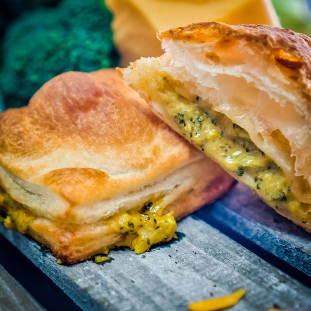 A generously filled croissant sandwich on a bakery board